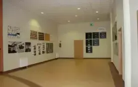 Aneks wystawowy I piętro, korytarz o beżowej podłodze i jasnoż&oacute;łtych ścianach, na kt&oacute;rych wywieszono obrazy w ramach wystawy.