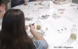 Kobieta w przebraniu wraz z uczestnikami siedzą przy stole.