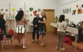 Sala OIA, przy stolikach siedzą zaproszeni goście, na tle wystawy przemawiają dwie kobiety.