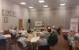 Publiczność podczas spotkania. Około 40 os&oacute;b siedzi przy stolikach i uczestniczy w spotkaniu.