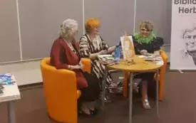 (Od lewej): Marianna Lis, Barbara Schroeder i Elżbieta Olszewska-Schilling siedzą przy stole na pomarańczowych fotelach i prowadzą dyskusję.