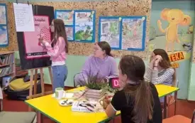 Trzy nastolatki siedzą przy stole, a czwarta zapisuje na tablicy problemy, kt&oacute;re pojawiły się w książce.