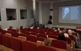 Publiczność zgromadzona w sali audytoryjnej, w tle wykład