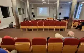 Sala audytoryjna z publicznością, w tle wykład jednego z prelegent&oacute;w