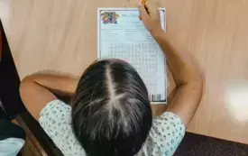 Dziecko trzyma w dłoni wykonaną na zajęciach papierową zakładkę w kształcie żabki.