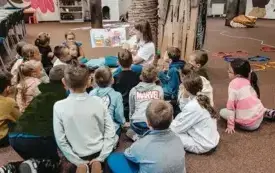 Bibliotekarka czyta dzieciom książkę i pokazuje ilustracje.
