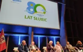 Paneliści siedzący na scenie. Za nimi wyświetla się logo obchod&oacute;w 80-lecia Słubic