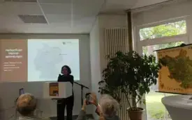 dr Magdalena Kamińska w trakcie wygłaszania referatu, za nią slajd z prezentacji