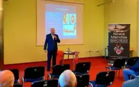 Roland semik w trakcie wykładu w sali, w tle slajd prezentacji, z boku slider z nazwą cyklu spotkań Nowa Marchia