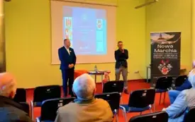 Stojący po prawej stronie w sali Patryk Lewandowski zapowiada stojącego po lewej Rolanda Semika, przed nimi publiczność a za nimi wyświetla się plakat wydarzenia 