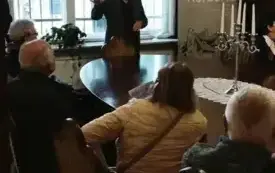 Kazimierz Ligocki opowiada seniorom o historii Willi Hansa Lehmanna. Uczestnicy spotkania siedzą przy owalnym stole w Willi Lehmanna.