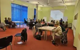 Osoby siedzą przy stołach podczas &bdquo;Akcja-orientacja! Biblioteka wielokulturowego czytelnika&rdquo;