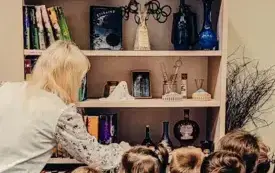 Grupa dzieci wraz z bibliotekarką oglądają regał przeznaczony Harremu Potterowi.