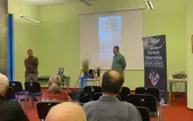 W sali pełnej ludzi Patryk Lewandowski (po lewej) zapowiada Konrada Hamkałę (po prawej). Między nimi stolik z dekoracją przypominającą Odrę. Z boku rollup cyklu spotkań Nowa Marchia