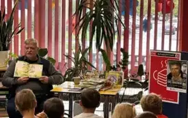 Mężczyzna czyta grupie dzieci książeczkę swojego autorstwa