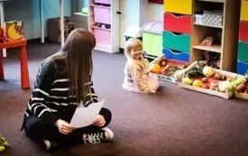 Na pierwszym planie Pani Bibliotekarka i uczestniczka cyklicznych zajęć. W tle stragan z owocami i warzywami.