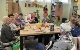 prowadząca trzyma w rękach plakat z informacją o konkursie &bdquo; Moje literackie fascynacje&rdquo;