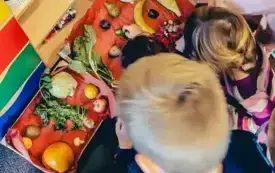 Dziewczynka dekoruje wycięte z papieru winogrono. 