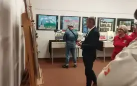 Oglądanie wystawy przez autor&oacute;w wystawy pt. "Wędr&oacute;wka przez historię. Moje ulubione zabytki Gorzowa". W tle Przewodniczący Rady Miasta - Robert Surowiec.