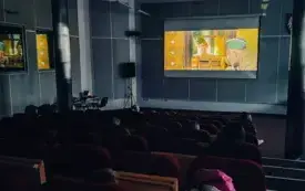 Wnętrze bibliotecznej auli. Na ekranie scena z filmu. Na pierwszym planie widzowie seansu. 