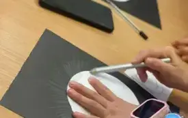 Wykonywanie pracy plastycznej przy użyciu czarnej kartki ,białego papieru i kredek.