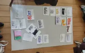 Ułożone na jasnym dywanie ponad dwadzieścia kartek z tekstami stworzonymi metodą blackout poetry