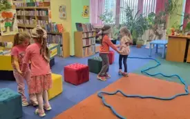 Dwie pary dziewczynek pokonują tor przeszk&oacute;d. Jedna osoba z każdej pary ma zawiązane oczy, a druga ją prowadzi.