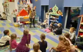 Animatorka stoi trzymając kukiełkę wśr&oacute;d dzieci siedzących na dywanie.