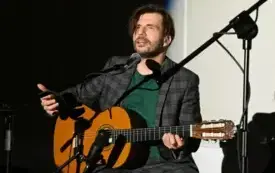 Koncert Limboskiego. Kadr przedstawiający Limboskiego trzymającego gitarę i przemawiającego do mikrofonu.