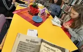Trzy dziewczynki rozwiązują test osobowości z książki przy stole