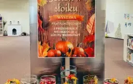Plakat promujący wystawę &bdquo;Jesień w słoiku&rdquo;. Pod plakatem na stole prace dzieci z grupy &bdquo;Biedronki&rdquo; z Przedszkola Miejskiego nr 12 w Gorzowie Wielkopolskim.