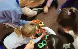 Dzieci zbierają pęsetami kolorowe pompony.