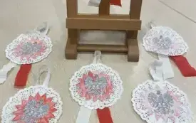 Na stoliku leży pięć biało-czerwonych kotylion&oacute;w, kotylion na minisztaludze drewnianej.