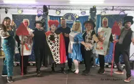 Dziewięć os&oacute;b w przebraniach stoi na scenie.