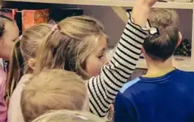 Dzieci oglądają książki na p&oacute;łkach.