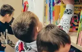 Dzieci oglądają książki na p&oacute;łkach.