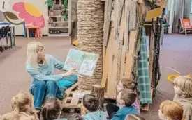Bibliotekarka czyta dzieciom książkę pt.: &bdquo;Najwyższa na świecie wieża z książek&rdquo;