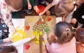 Przedszkolaki wypełniają drzewko pofarbowanym ryżem, fasolą i makaronem. 