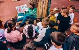 Bibliotekarka czyta uczniom książkę &bdquo;Poszukiwany! Tajemniczy pożeracz książek&rdquo; Emily Mackenzie.