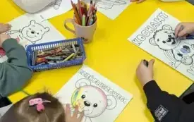 Przedszkolaki kolorują misie siedząc przy stole.