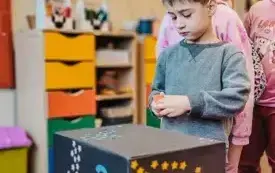 Chłopiec losuje kolorową karteczkę z magicznego pudełka. 