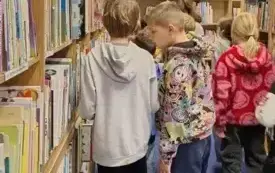 Uczniowie stoją przy regałach. Wyszukują książki o Afryce.