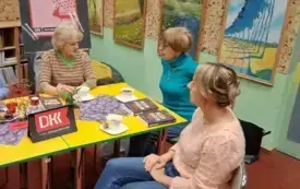 Trzy Klubowiczki siedzą. Na stole leżą książki.