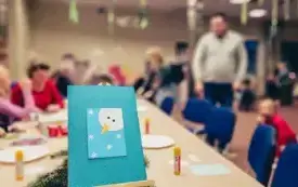 Kartka z bałwankiem., W tle uczestnicy spotkania mikołajkowego.