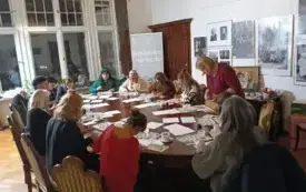Prowadząca warsztaty Olga Paszkowska pochyla się nad pracą jednego z uczestnik&oacute;w