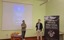 Grzegorz Urbanek stojący po prawej przedstawia Dawida Buczkiewicza stojącego po lewej stronie. Koło Urbanka rollup z logo Nowej Marchii