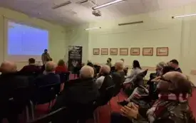 Publiczność zgromadzona w sali audytoryjnej, w tle wykład