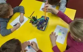 Dzieci przy stole kolorują pierniki.