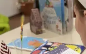 Kobieta czyta książkę, w tle na stoliku toją i leżą książeki.