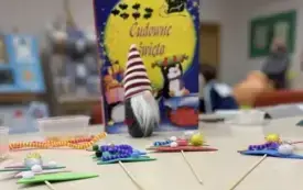 Na stoliku stoi książka o tytule Cudowne święta, skrzat i leżą 4 płaskie choinki na piku wykonane przez dzieci.  